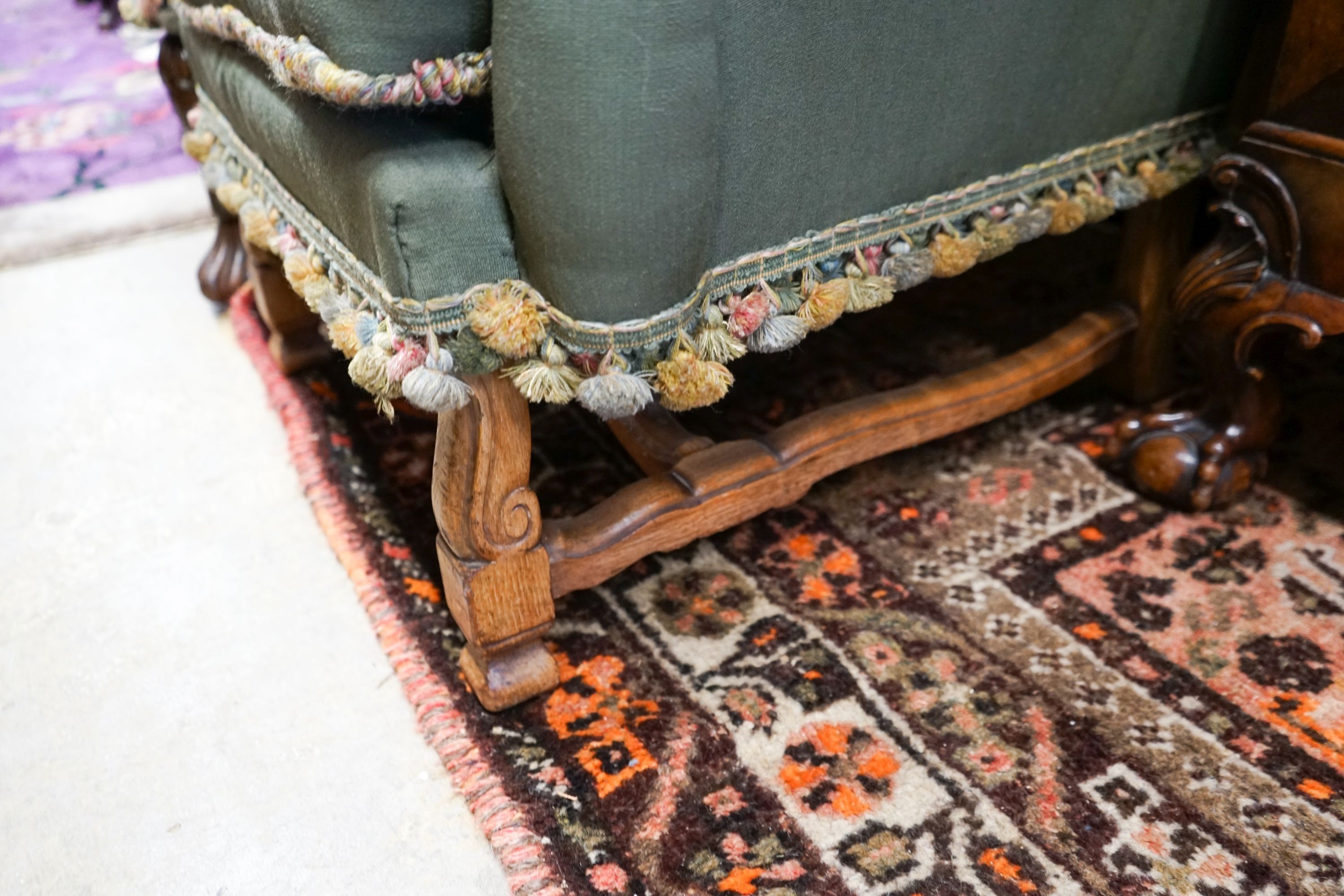 Two armchairs with shaped backs, each upholstered in green with embroidered flowers, on shaped cross stretchers with scrolled feet, larger width 80cm, depth 70cm, height 102cm